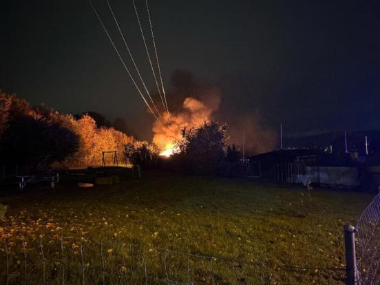 Schrebergartenhaus in Vollbrand, Flammen steigen in den Nachthimmel