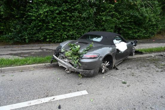 Das durch den Unfall schwer beschädigte Fahrzeug steht auf der Strasse; die Räder sind abgerissen