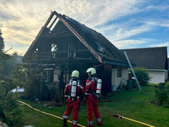 Feuerwehrleute vor einem ausgebrannten Dachstock