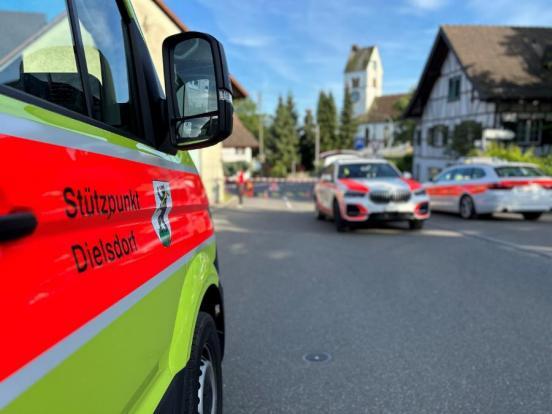 Seitentür eines Feuerwehrfahrzeugs; Im Hintergrund Polizeifahrzeuge auf der Strasse  und eine abgesperrte Unfallstelle