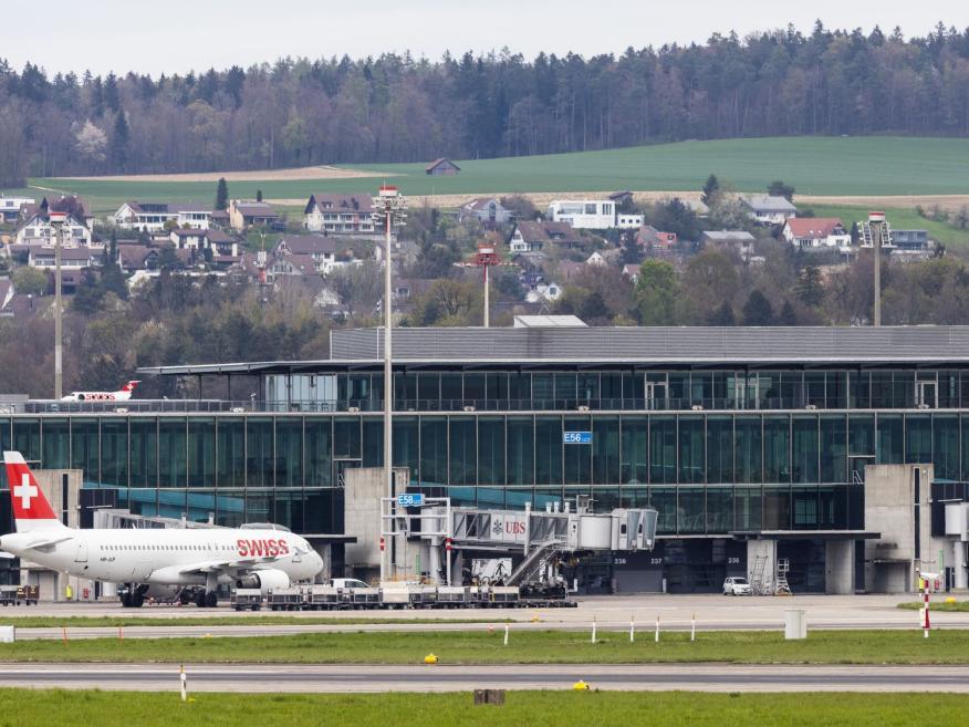 Blick vom Rollfeld auf den Flughafen Zürich mit davorstehendem Swiss Flugzeug