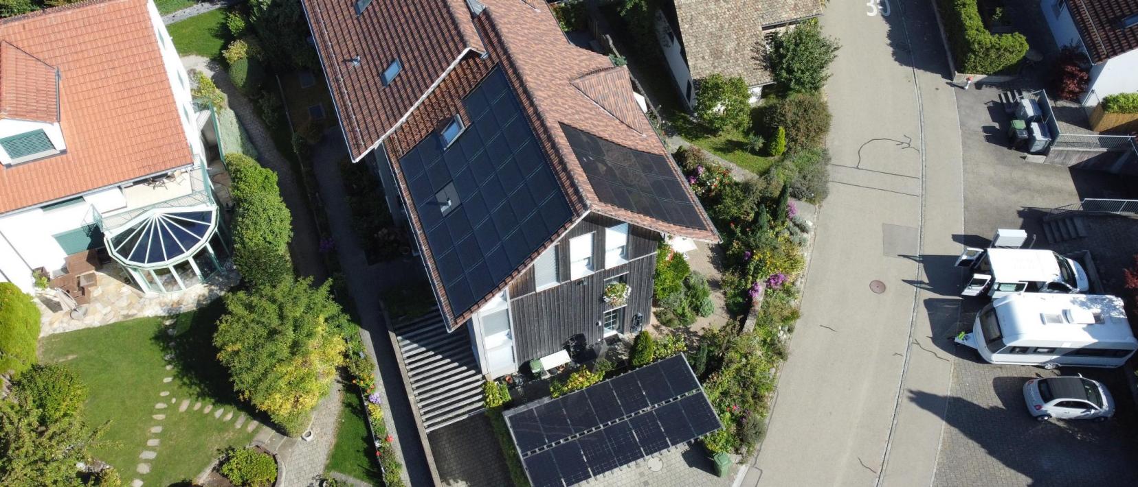 Auf einer Luftaufnahme sieht man verschiedene Häuser. Auf einigen Hausdächern befinden sich Solarzellen.