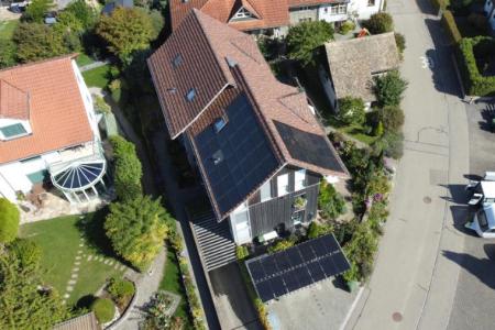 Auf einer Luftaufnahme sieht man verschiedene Häuser. Auf einem der Hausdächer befinden sich Solarzellen. 