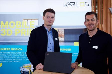  Arthur Martinevski und Markus Frasch von der Putzmeister 3D Tec GmbH stehen nebeneinander und lächeln in die Kamera. 