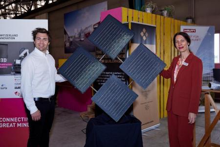 Mitarbeitende von Solskin und Zurich Soft Robotics stehen neben ihrem Produkt, der Solskin Gebäudehülle bestehend aus vier sschwarzen Quadraten, welche mit Solarzellen ausgestattet sind und sich unabhängig voneinander bewegen können. 