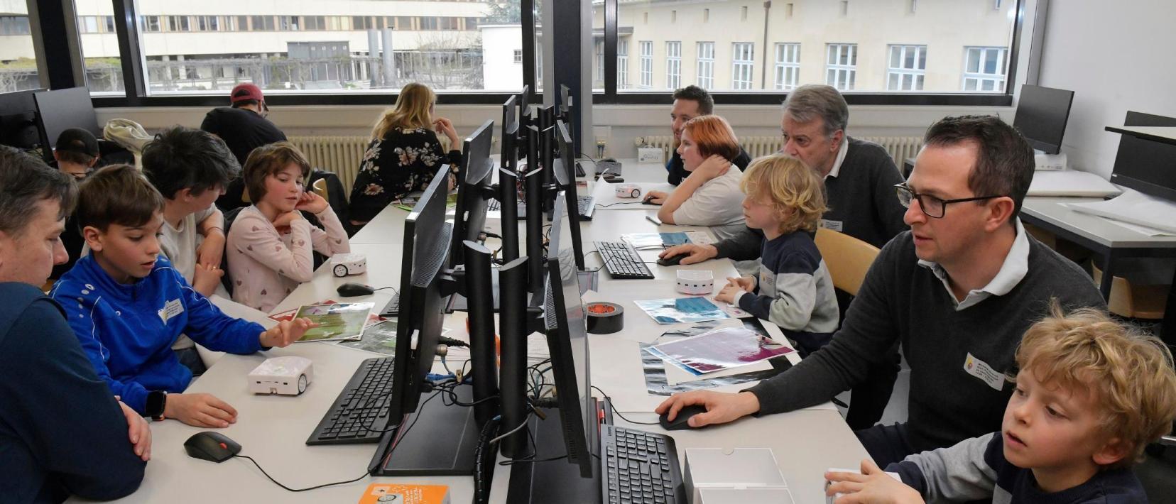 Erwachsene betreuen mehrere Kinder, die am Computer sitzen