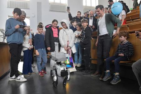 Kinder bestaunen einen Roboter, der sich am Boden bewegt