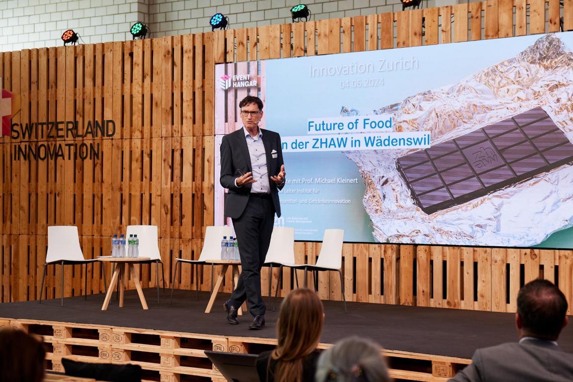 Prof. Michael Kleinert von der ZHAW präsentierte zum Thema «Future of Food» und beleuchtete innovative Ansätze zur nachhaltigen Lebensmittelproduktion, wie Verpackungen aus Kartoffelschalen und zusatzstofffreies Hamburgerbrot aus Sauerteig.